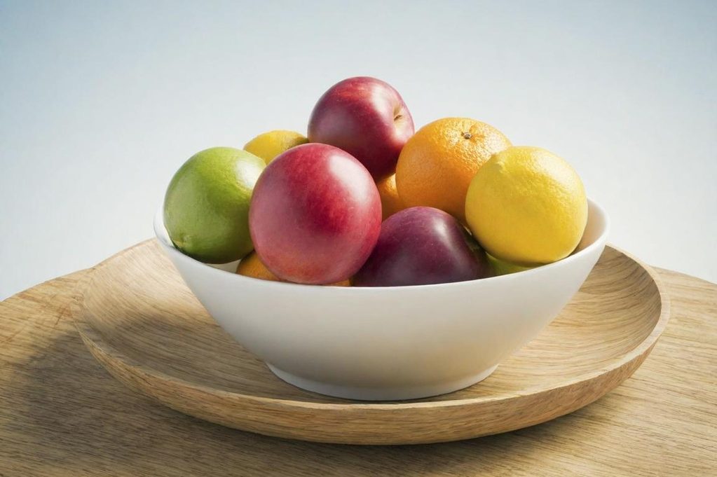 Obstschale Schüssel mit bunten Äpfeln, Orangen und Zitronen auf einer hölzernen Unterlage.